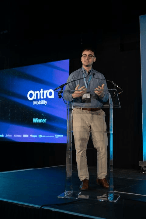 Ontra Mobility at the podium with a screen announcing the company as a winner